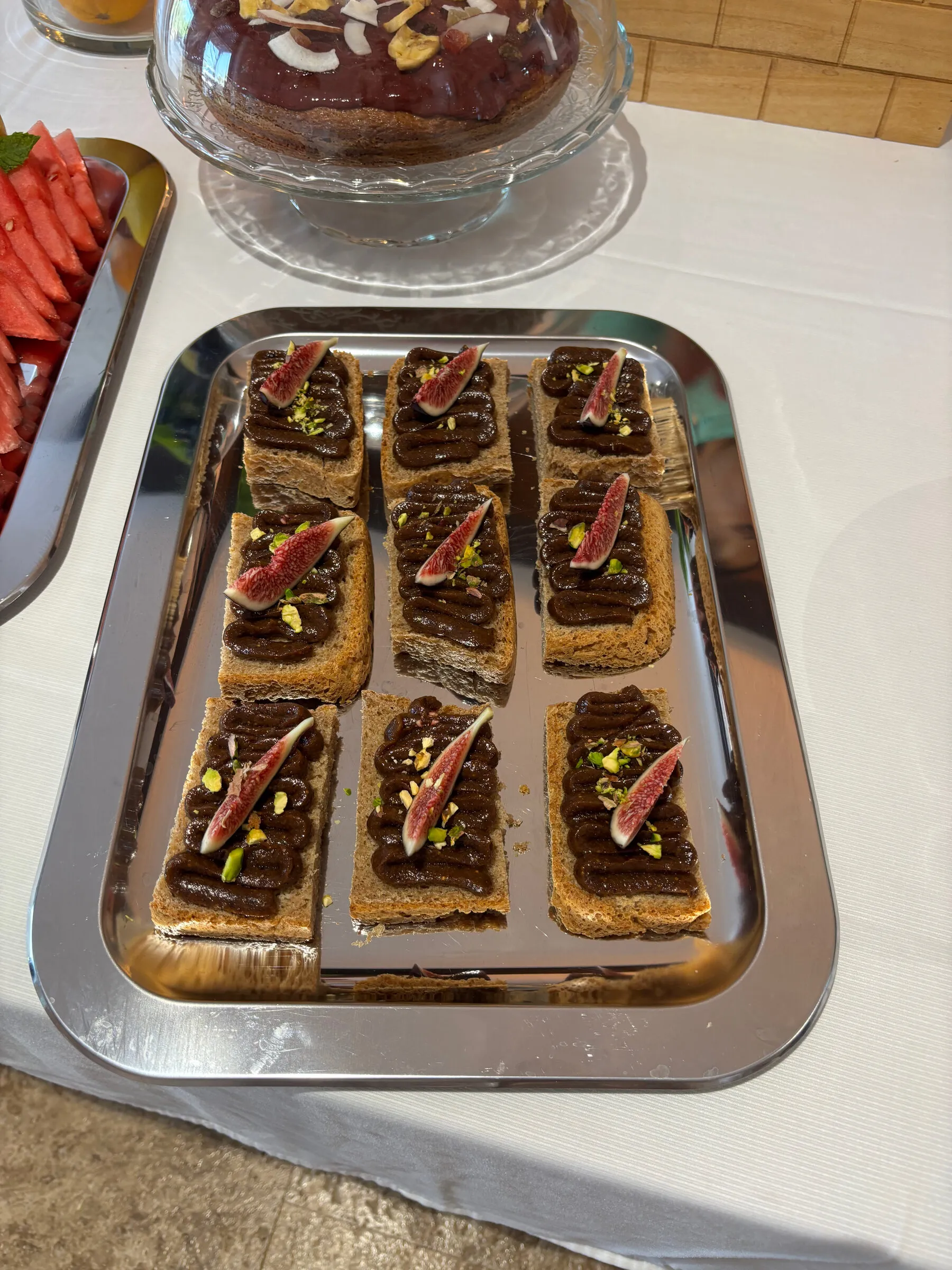 Toasts spread with dark ayurvedic fruit cream, topped with fresh fig and pistachio