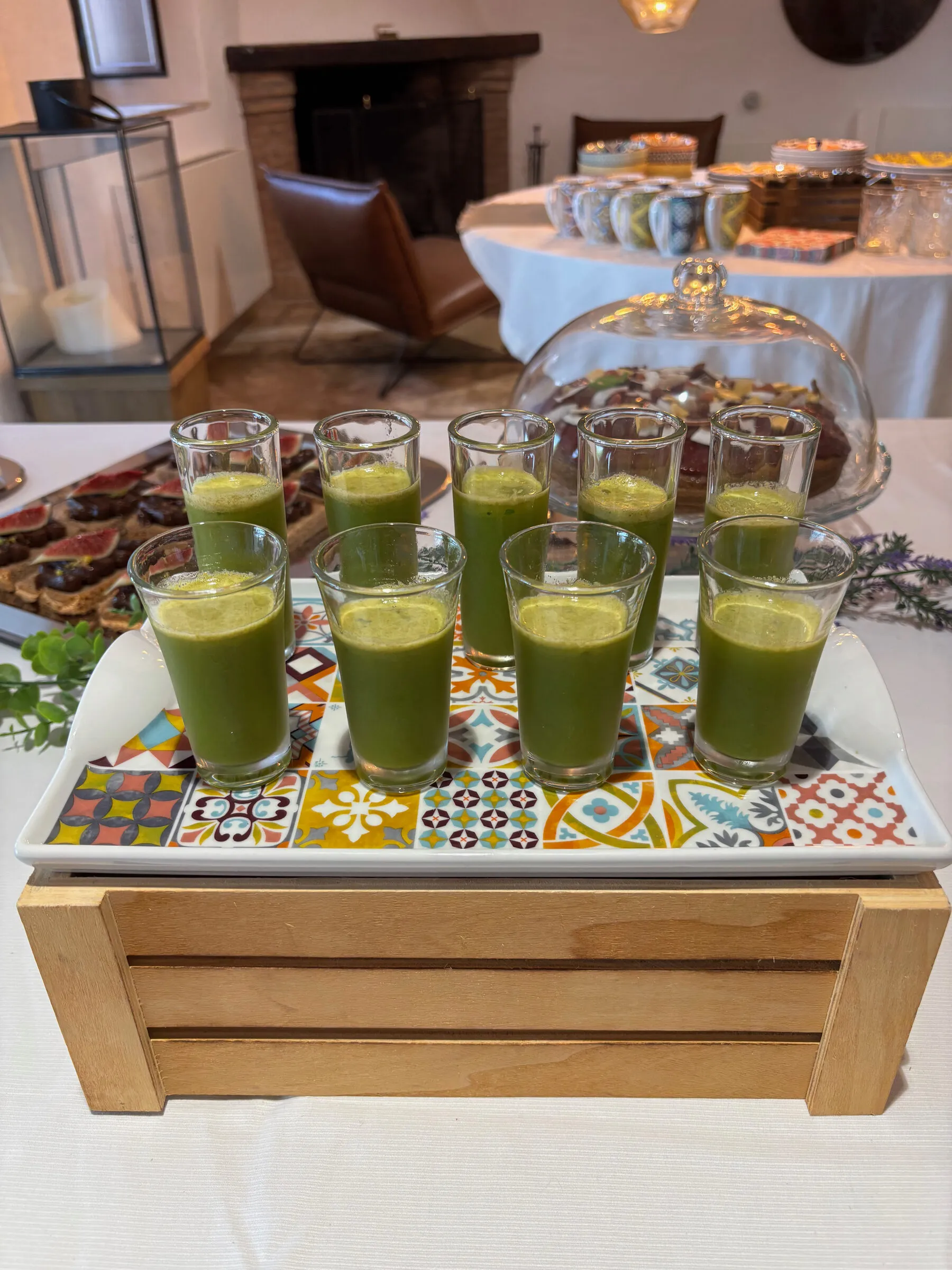 Ten glasses of green juice on a patterned tray