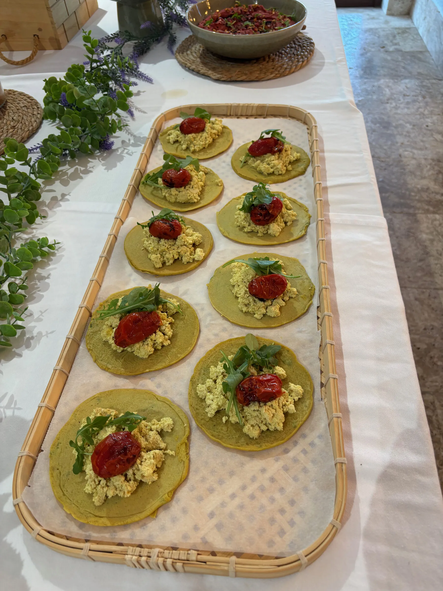 A long tray of buckwheat pancakes with scrambled tofu and roasted tomato